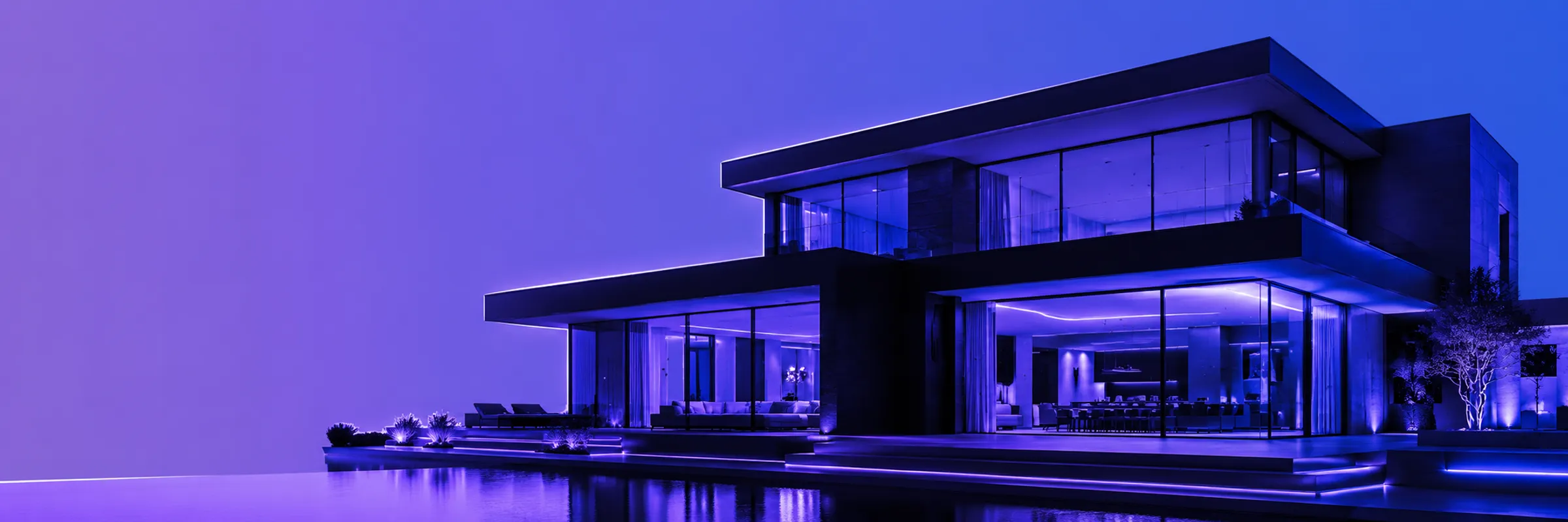 A modern glass-walled home lit from within at dusk